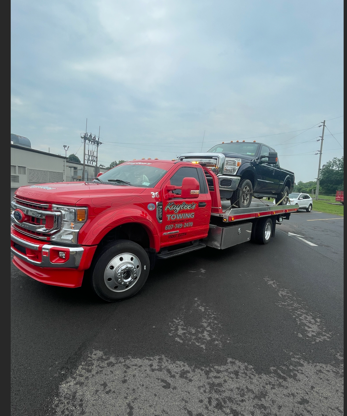 A red tow truck with a black truck on the back
