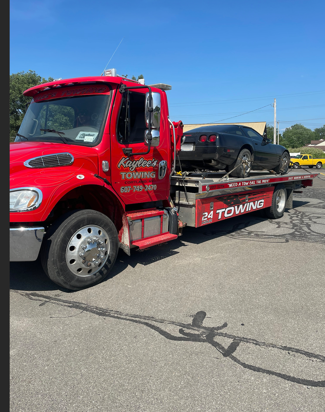 A red tow truck with a car on the back is parked on the side of the road.