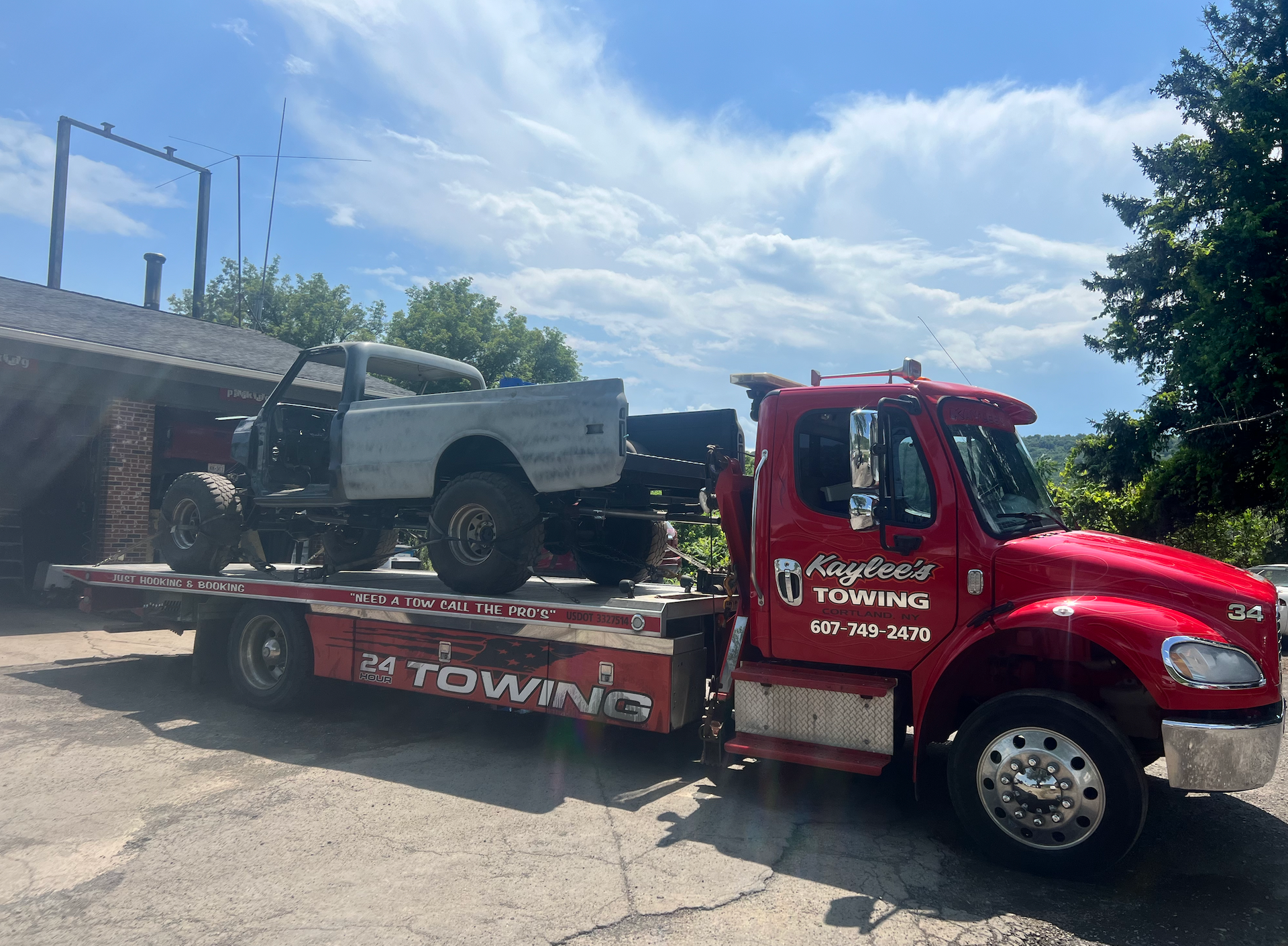 A red towing truck is carrying a truck and a jeep.