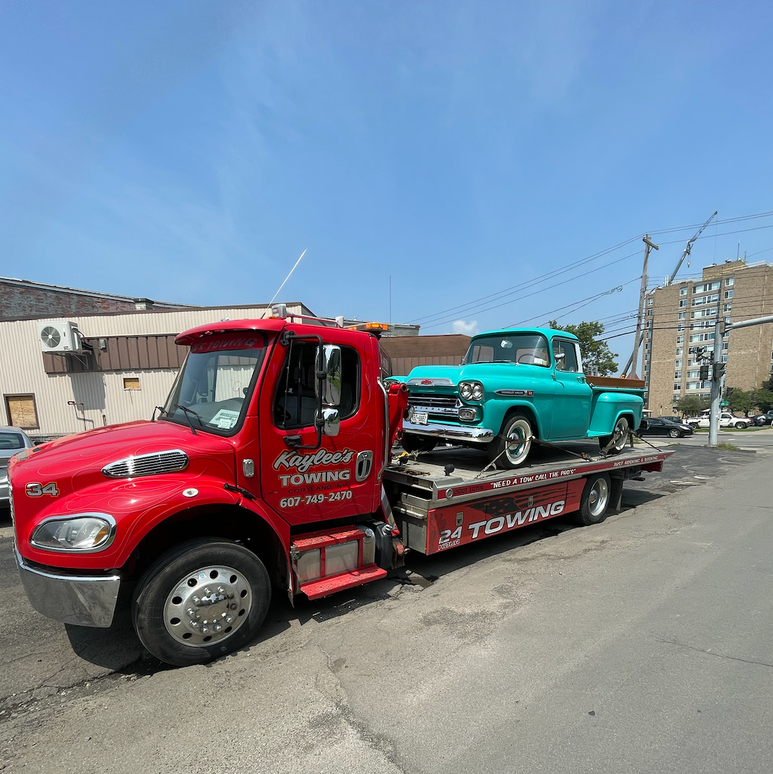 A red tow truck with a blue truck on the back