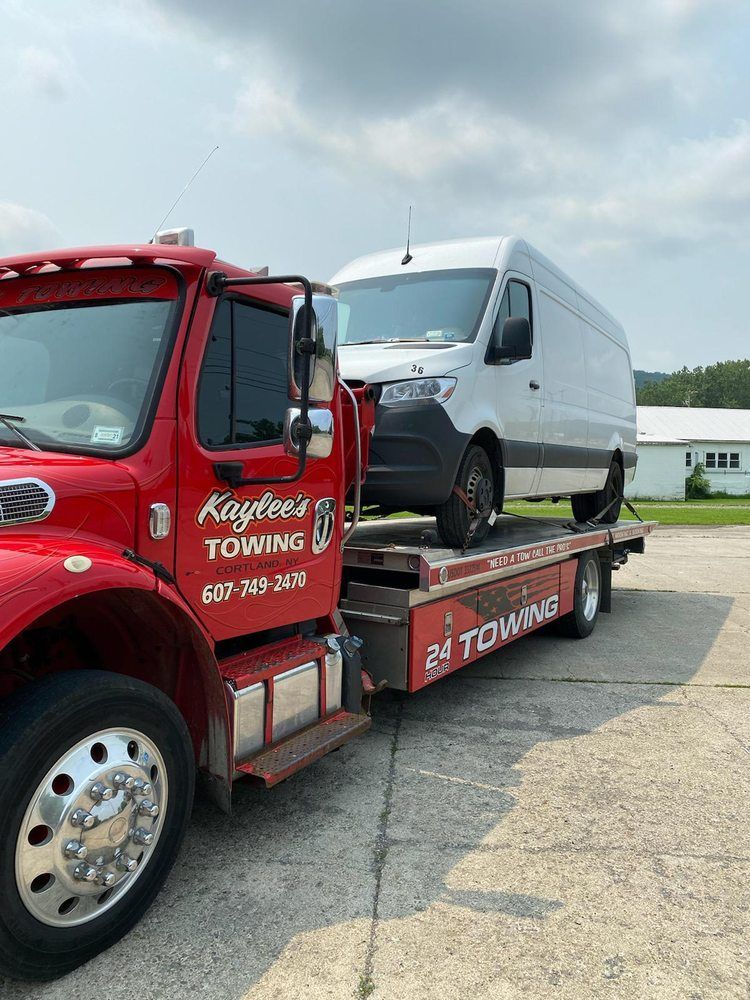 A red tow truck is towing a white van.