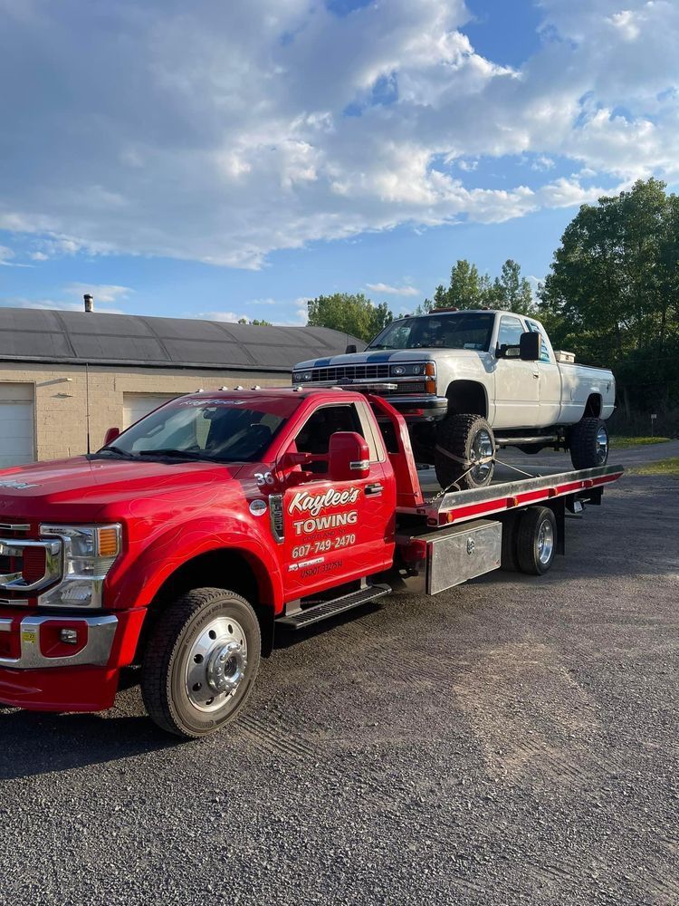 A red tow truck is towing a white truck.