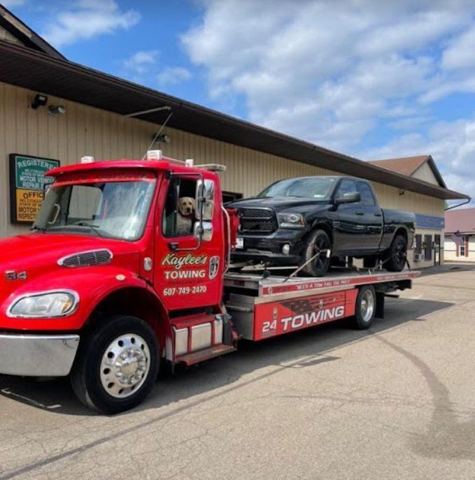 A red towing truck with a black truck on the back