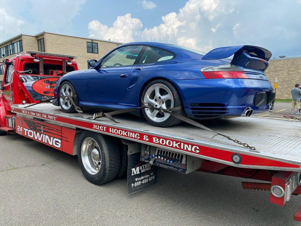 A blue car is sitting on top of a tow truck.