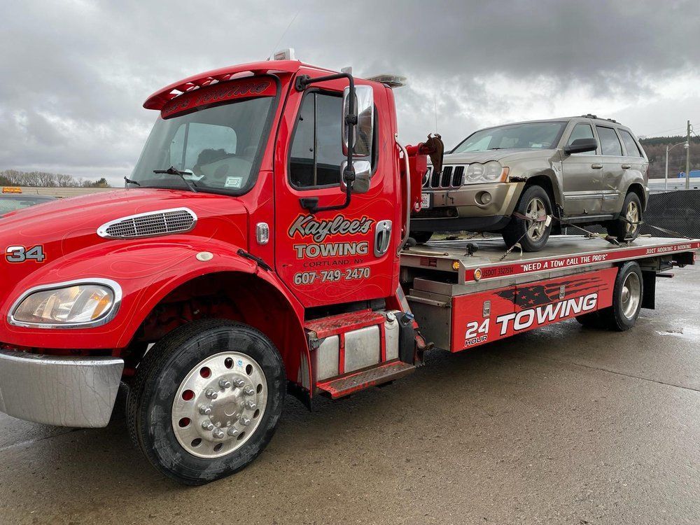 A red tow truck is carrying a jeep on the back of it.
