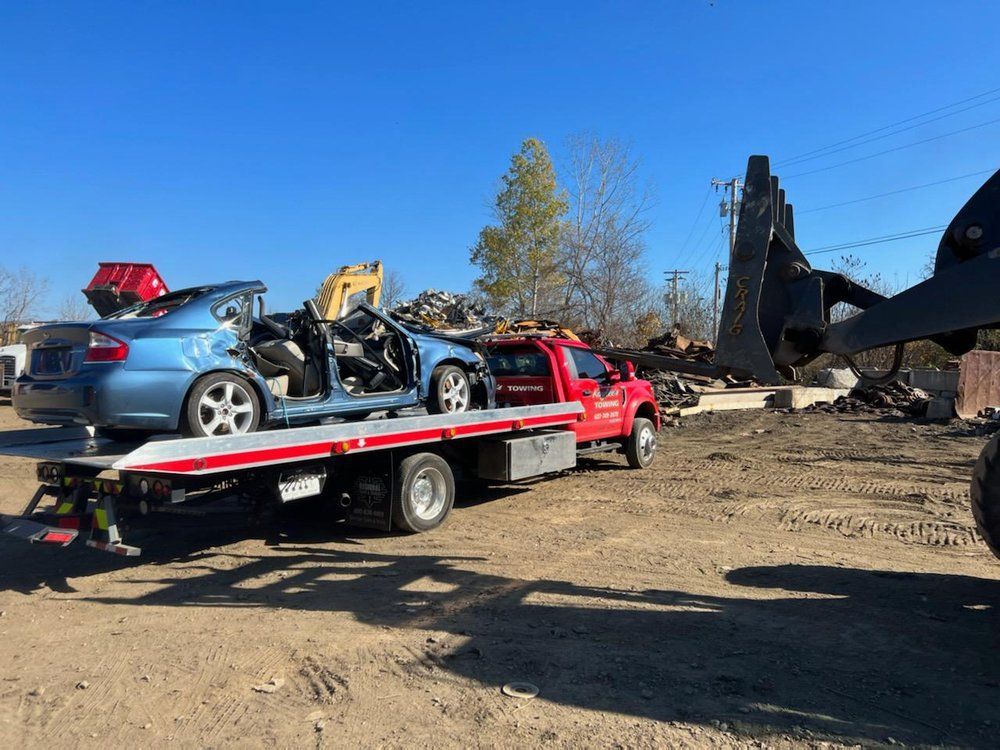 A tow truck with a blue car on the back of it