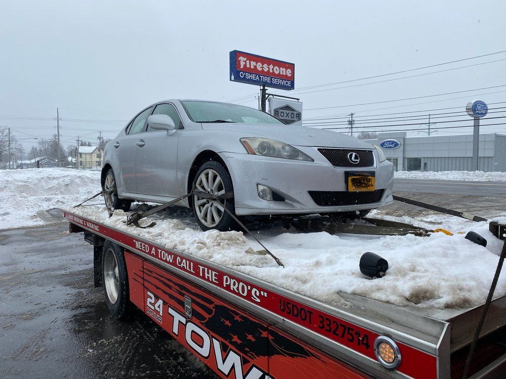 A silver car is sitting on top of a tow truck.