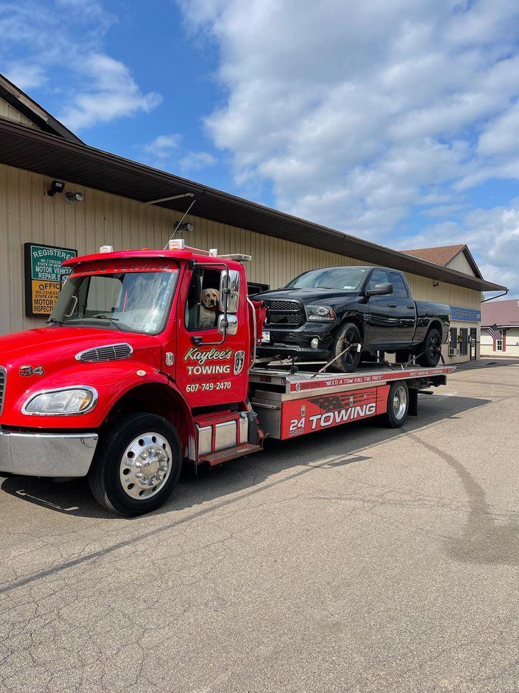 A red tow truck is towing a black truck.