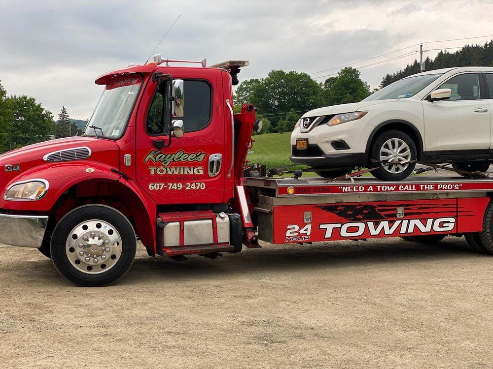 A red towing truck is towing a white suv.