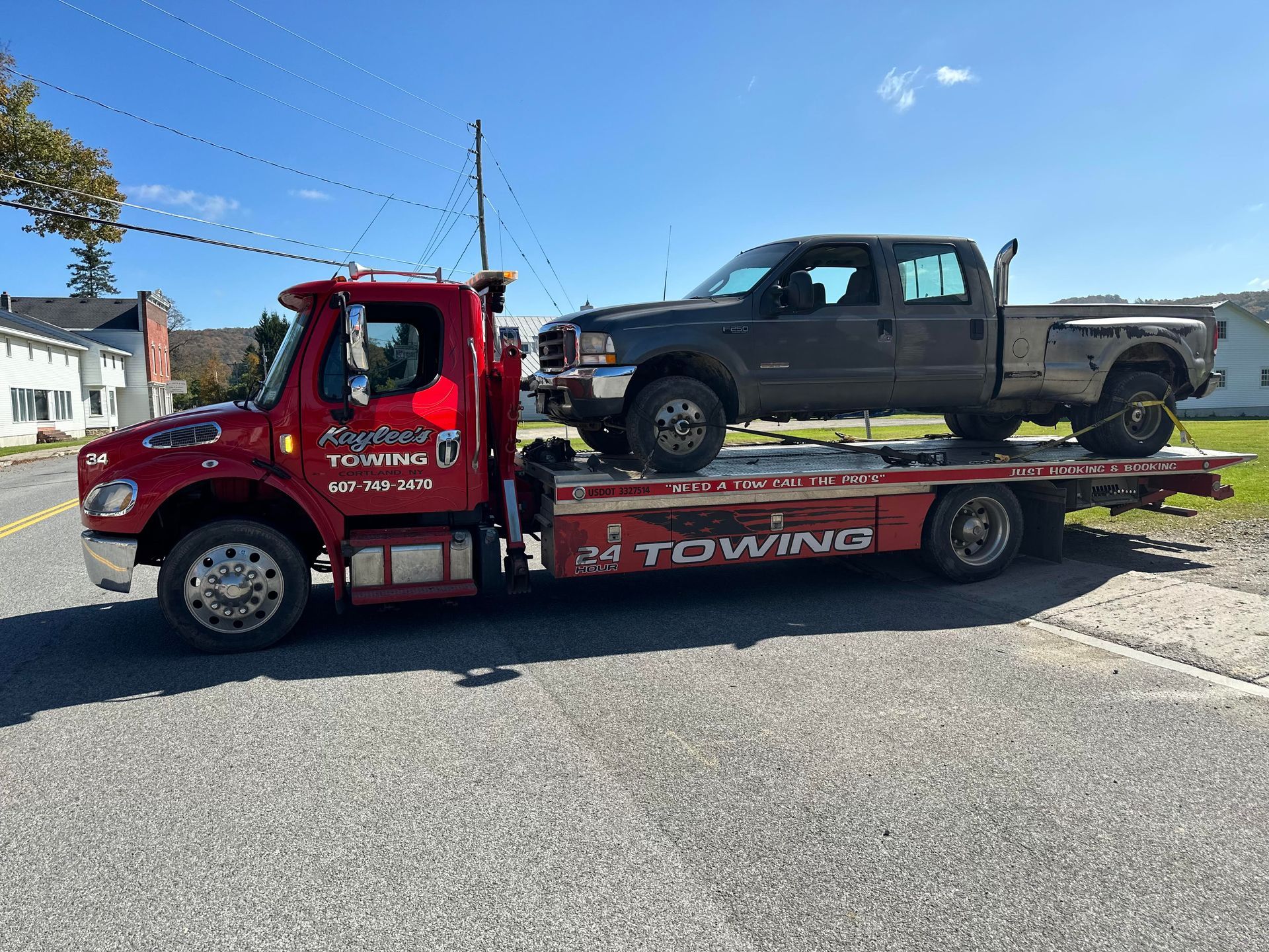 A tow truck is carrying a truck on the back of it.