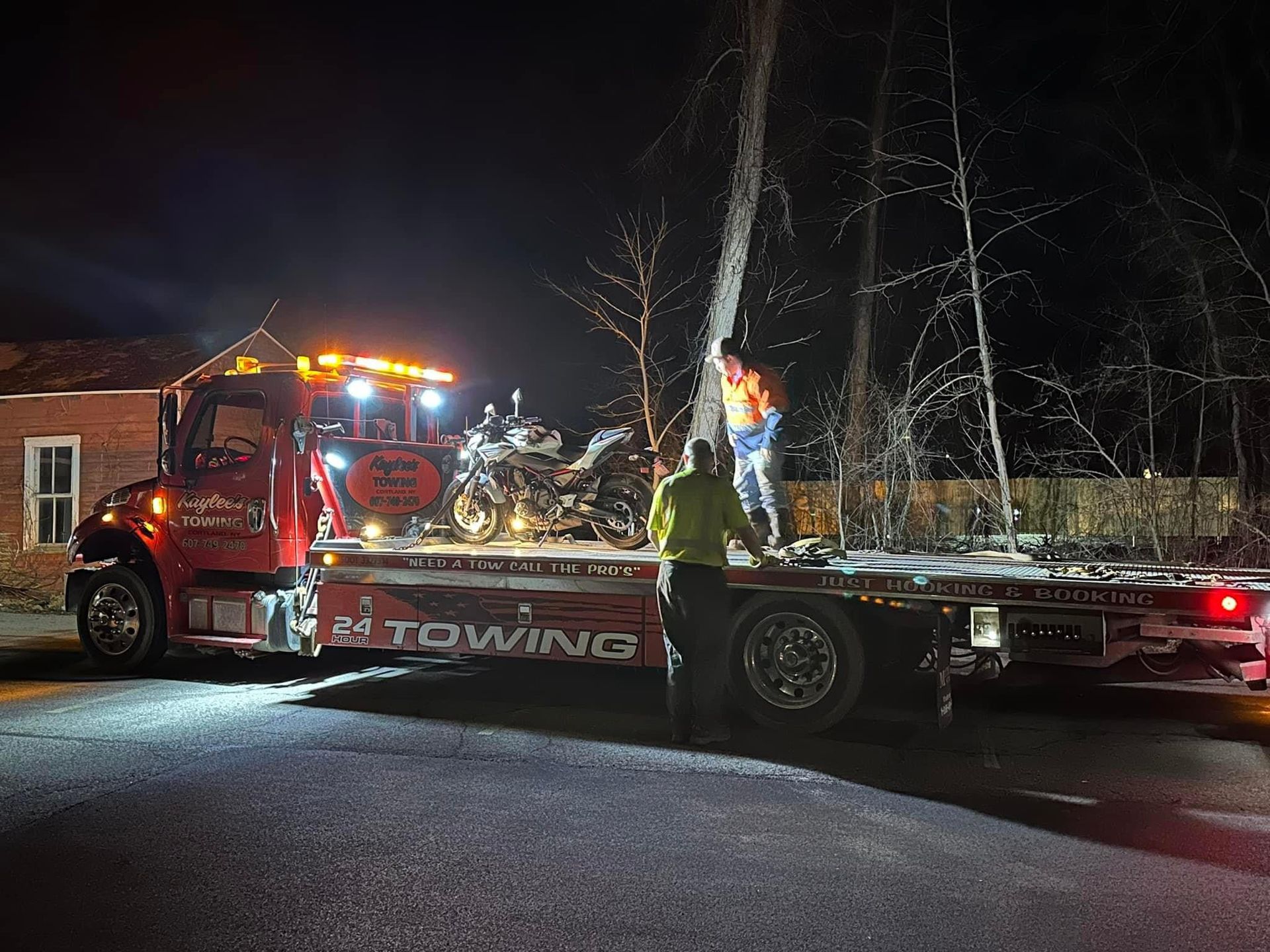 A tow truck is towing a motorcycle at night.