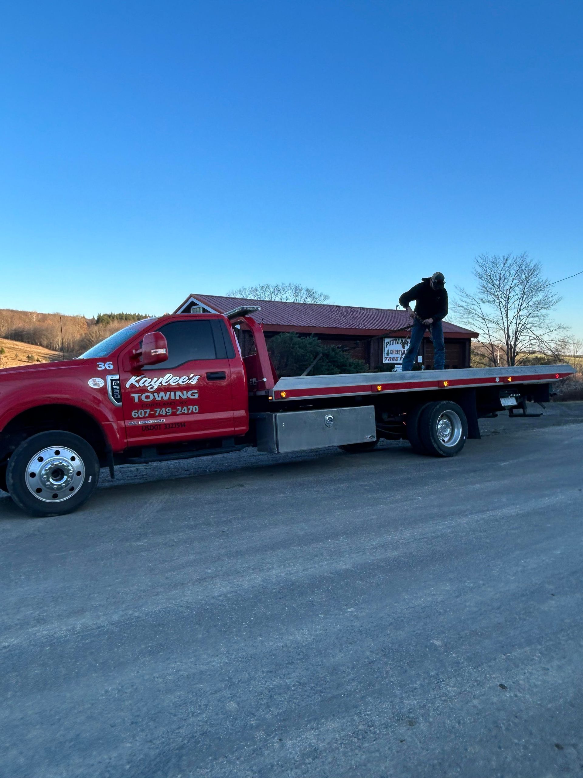A red tow truck is parked on the side of the road next to a house.