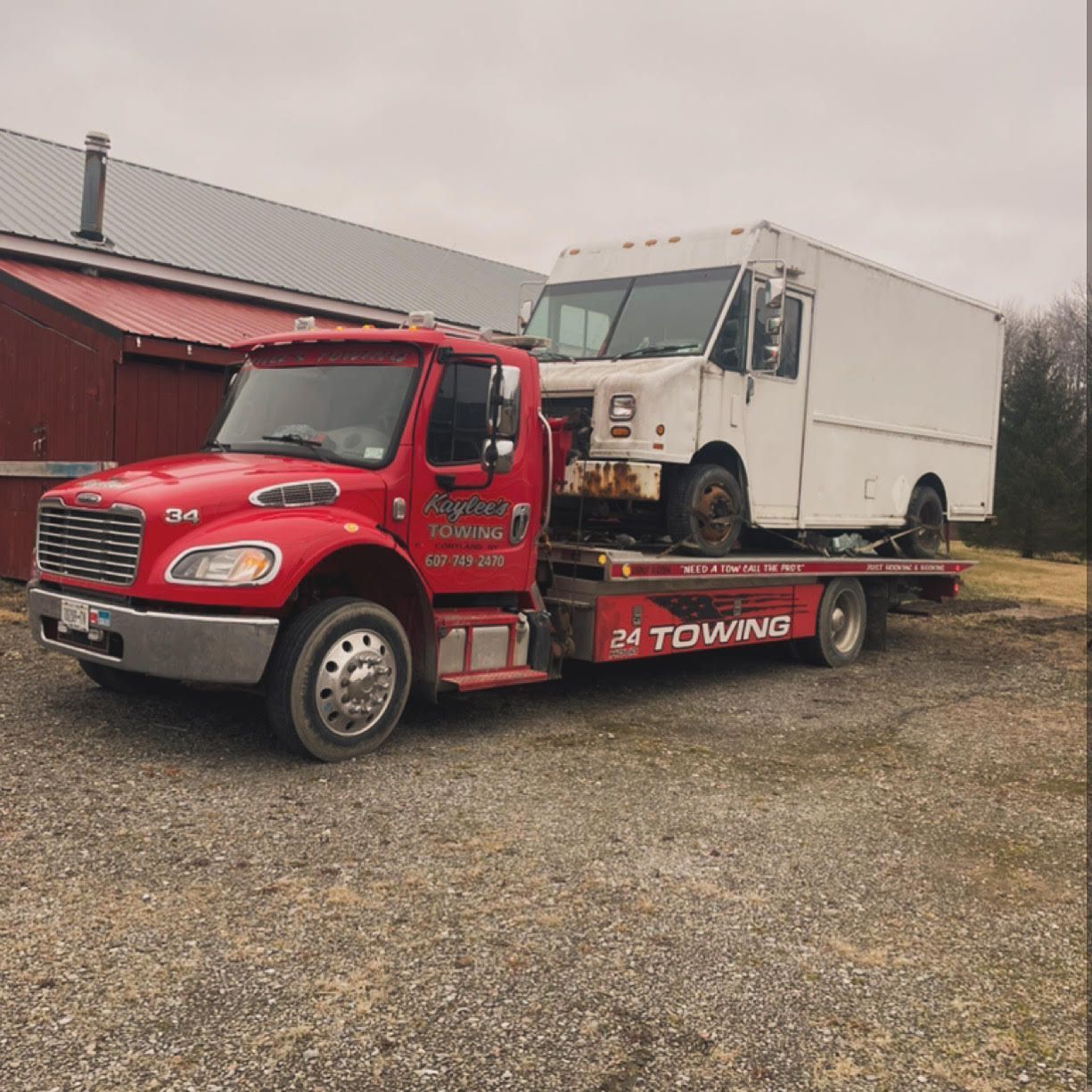 A red towing truck is carrying a white van