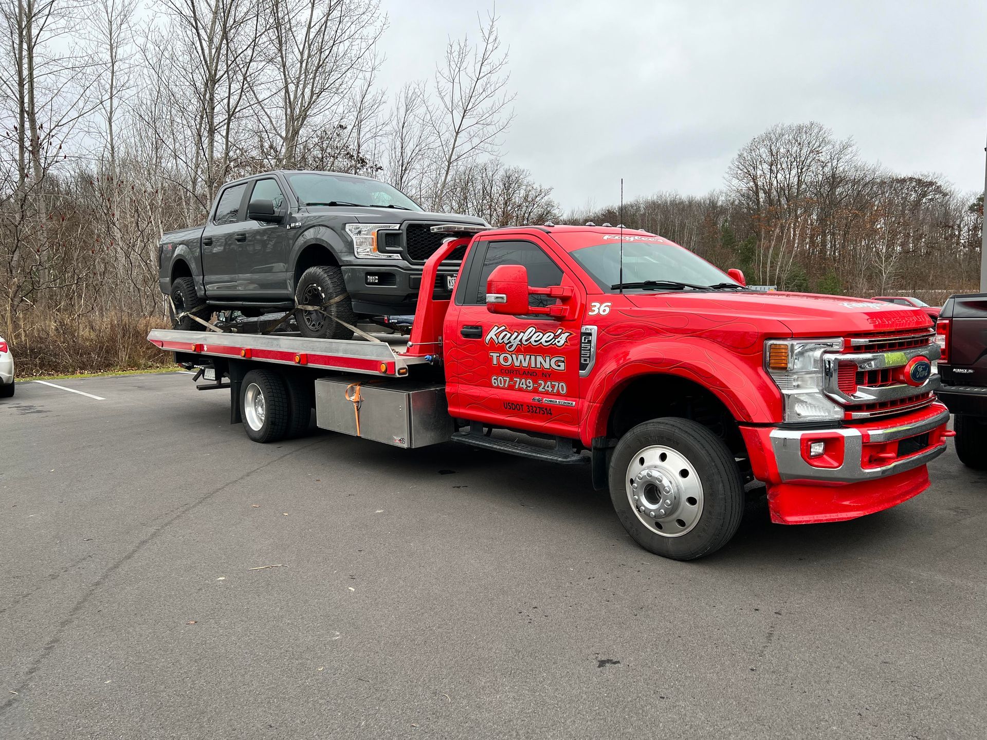 A red tow truck is towing a black truck.