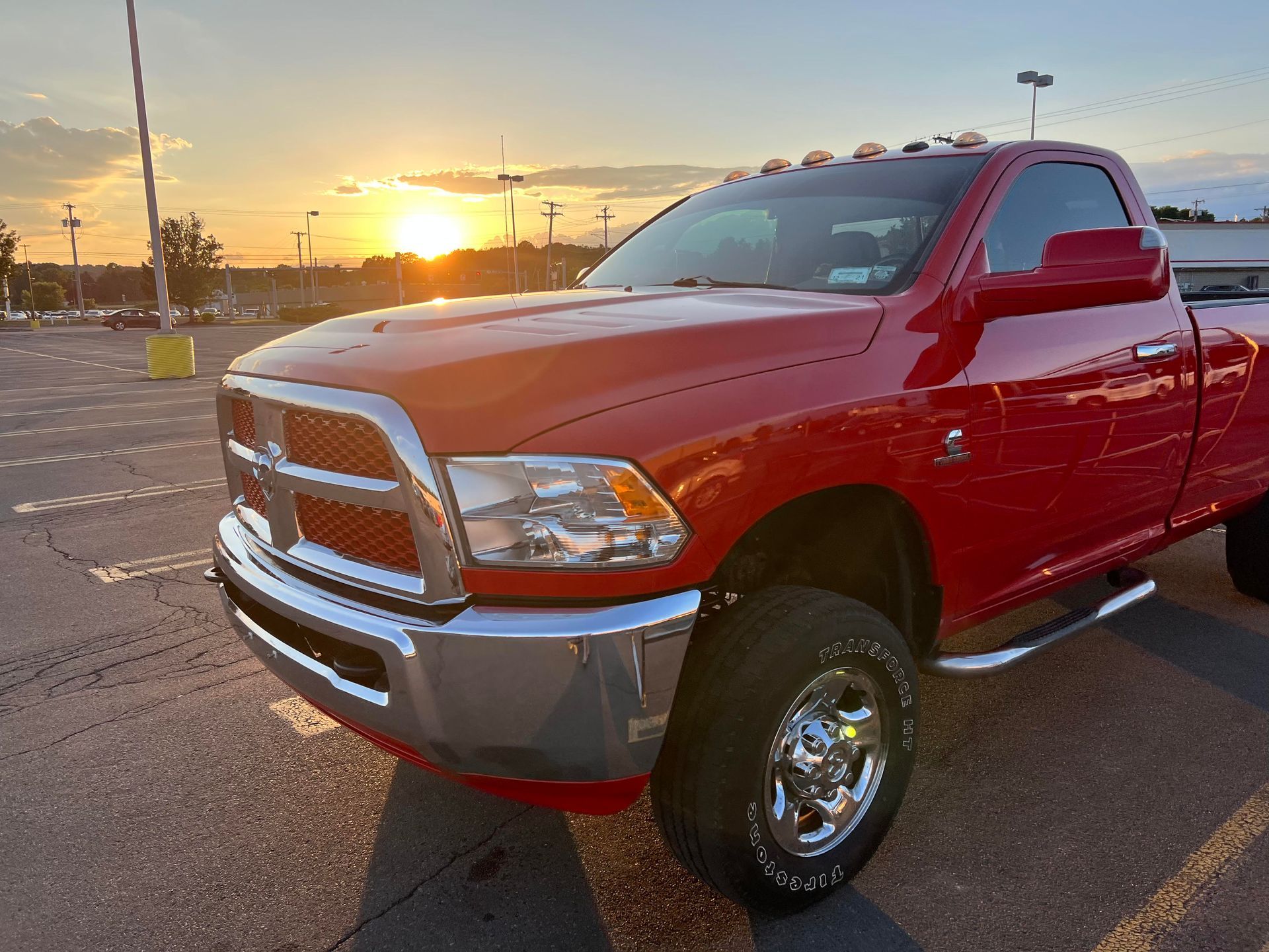 A red dodge ram truck is parked in a parking lot at sunset.