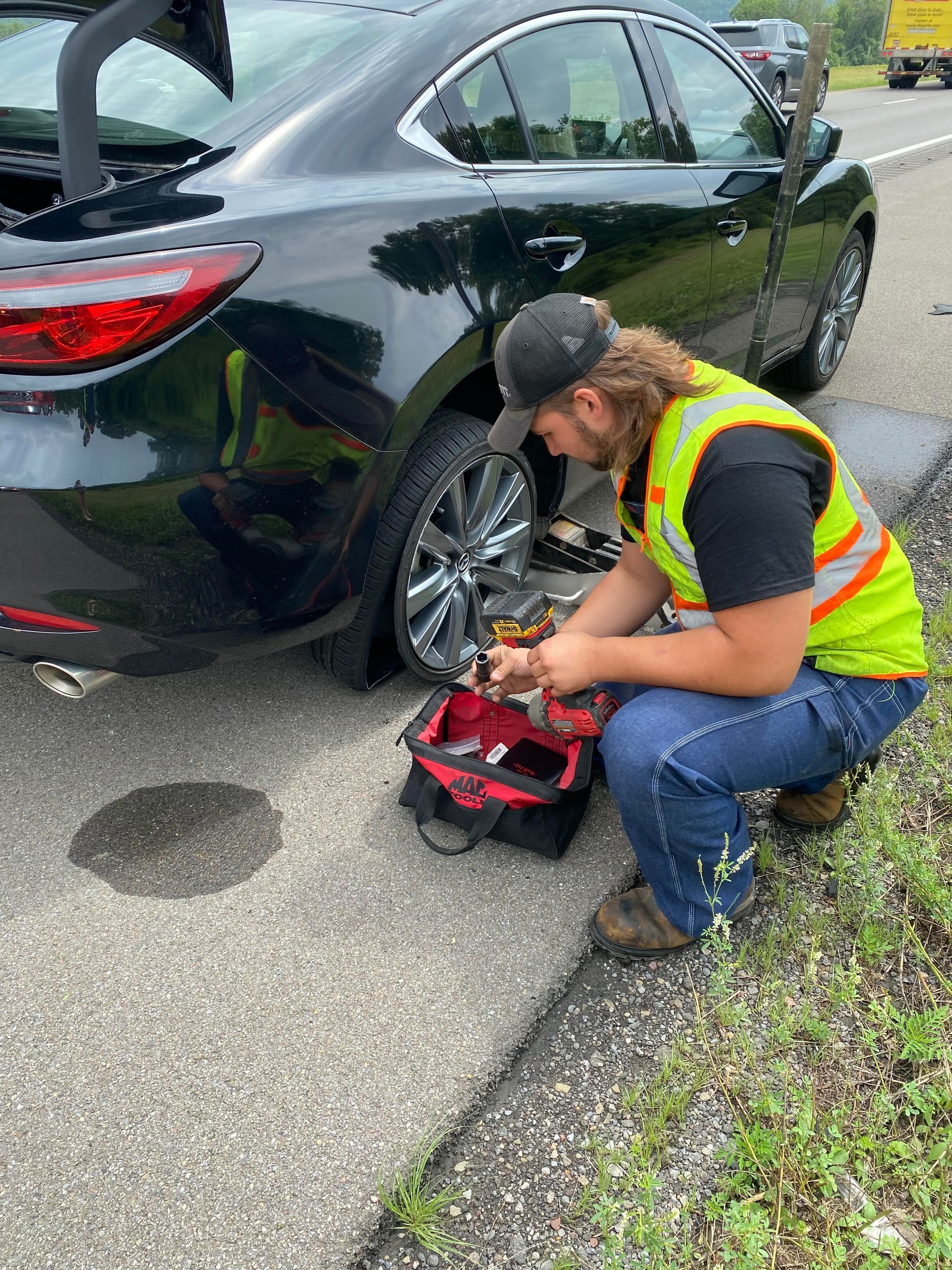 A man is working on a car on the side of the road.