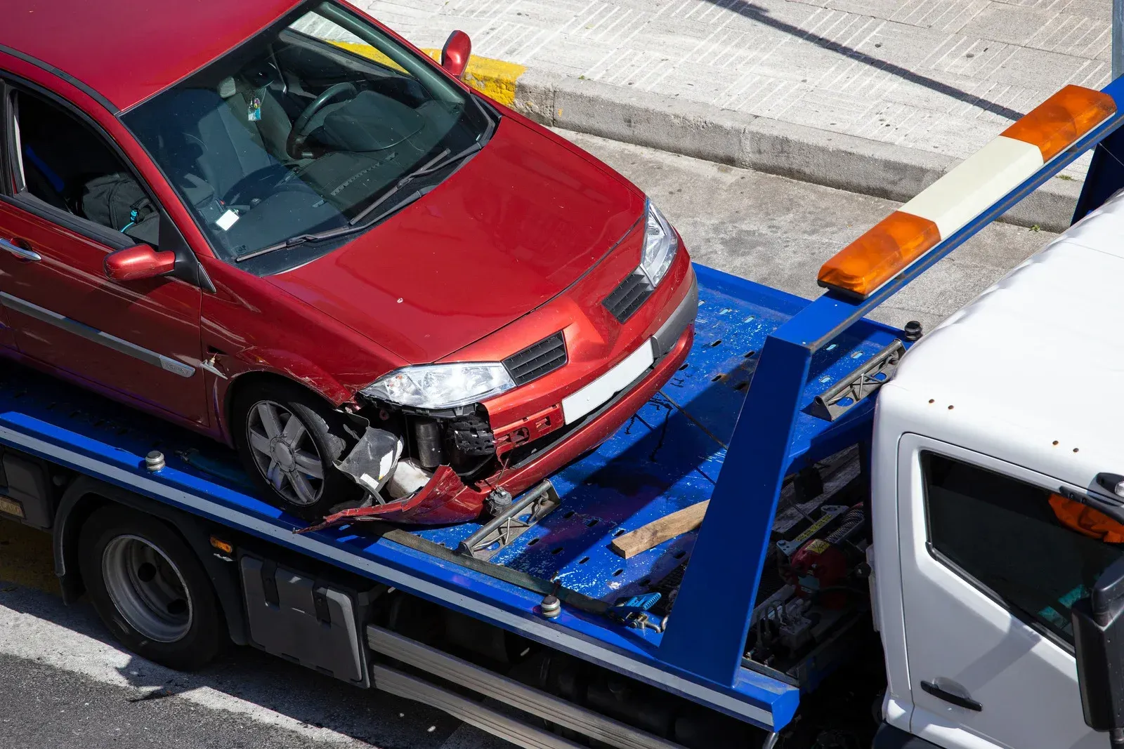 A damaged truck is sitting on top of a towing truck.