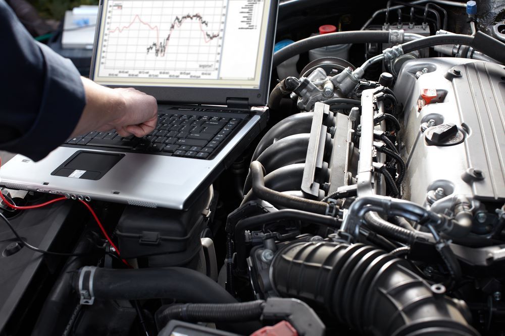 A Man is Working on a Car Engine With a Laptop — C J Mechanical In Berry, NSW