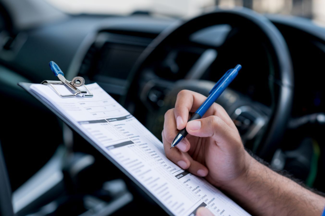 A Person Is Writing On A Clipboard In A Car — C J Mechanical In Berry, NSW