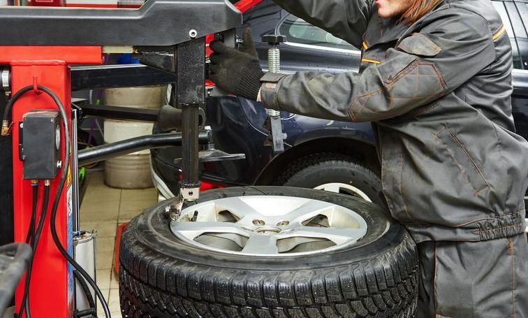 A Man is Changing a Tire on a Machine in a Garage — C J Mechanical In Berry, NSW