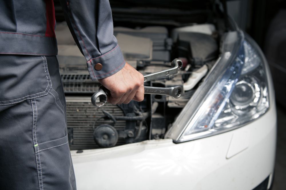 A Man is Holding a Wrench in Front of the Car — C J Mechanical in Berry, NSW