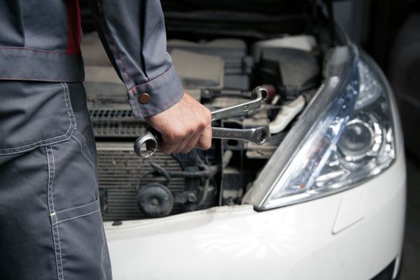A Man is Holding a Wrench in Front of the Car — C J Mechanical in Berry, NSW