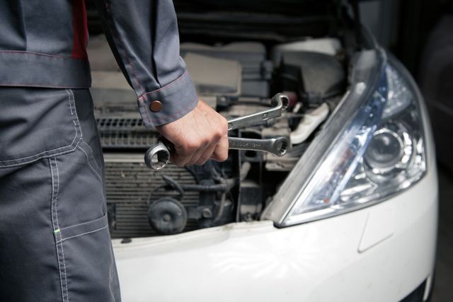 A Man is Holding a Wrench in Front of the Car — C J Mechanical in Berry, NSW