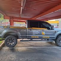 A pickup truck is parked under a canopy in a parking lot.