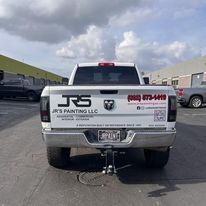 The back of a white truck is parked in a parking lot.