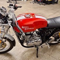 A red and white motorcycle is parked on the floor in a garage.