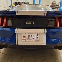 A blue mustang gt with a license plate that says jaa4hr is parked in a garage.