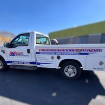 A white truck is parked on the side of the road in front of a building.