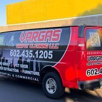 A red van is parked in front of a yellow building.