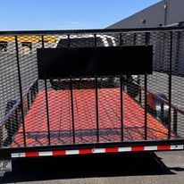 A red trailer is parked on the side of the road next to a truck.