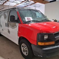 A red and white van is parked in a garage.