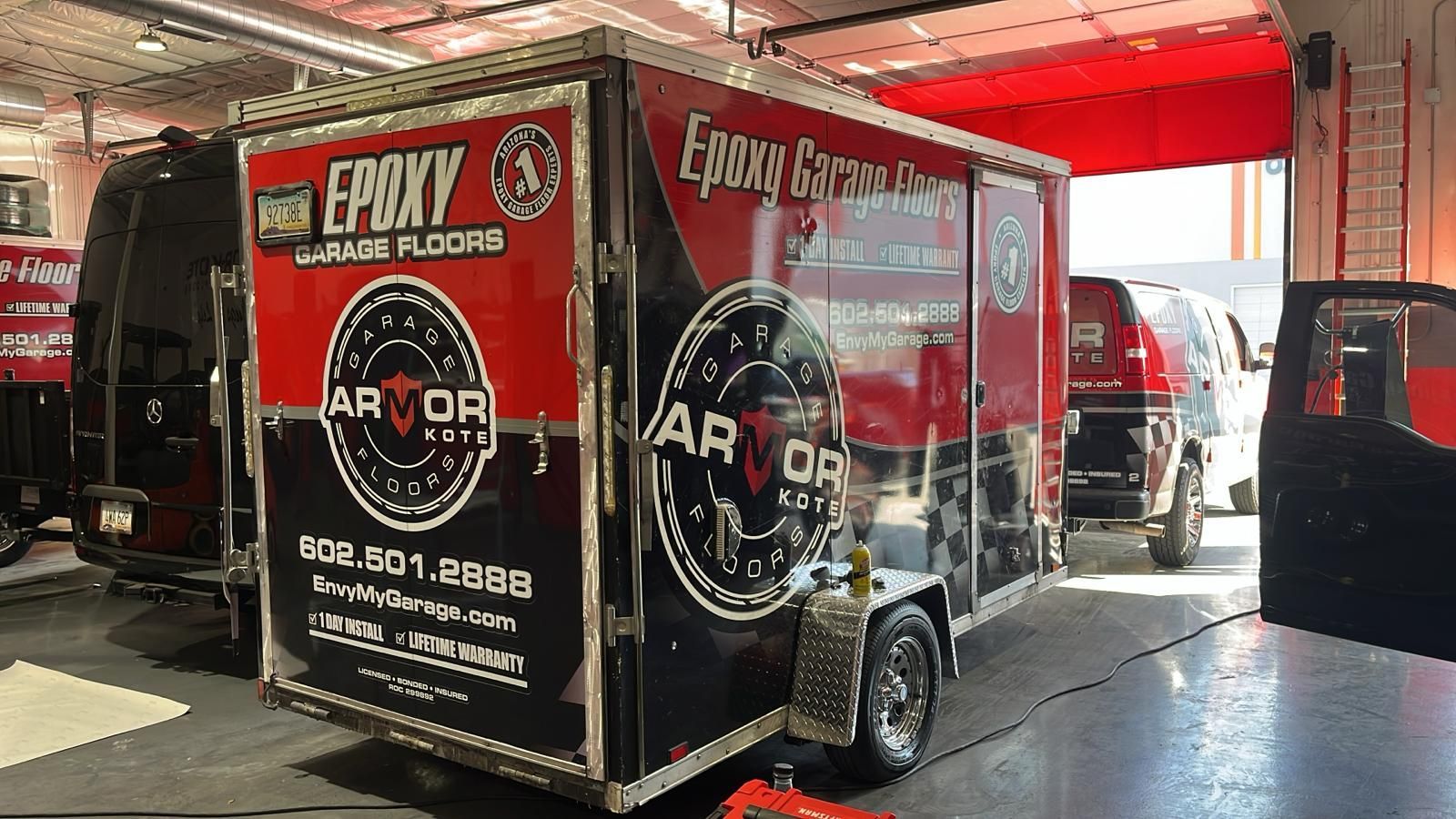 A red and black trailer is parked in a garage.