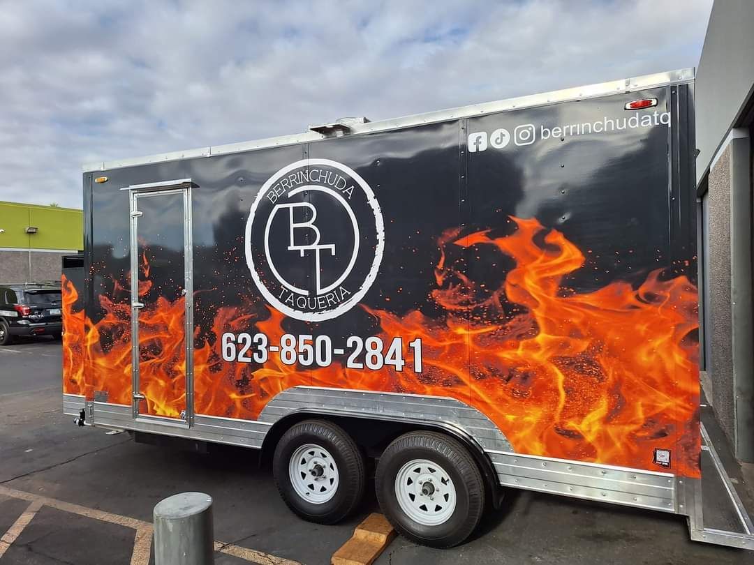 A trailer with flames on it is parked in a parking lot.