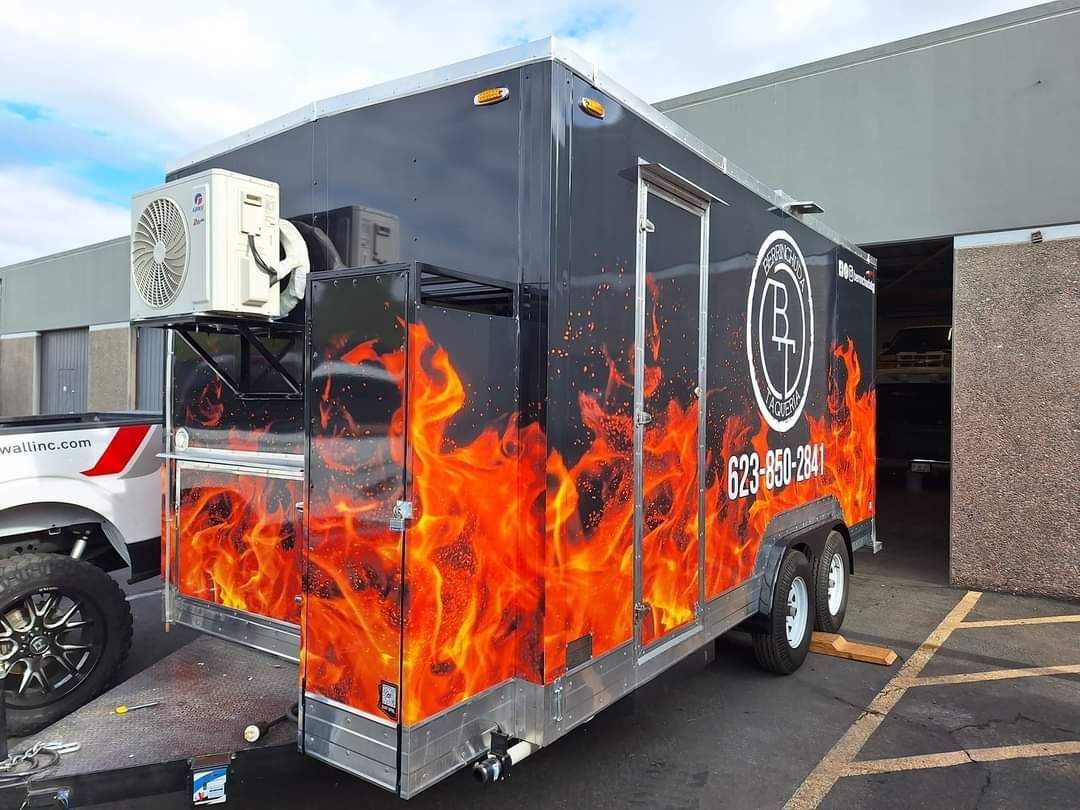 A trailer with flames painted on it is parked in a parking lot.