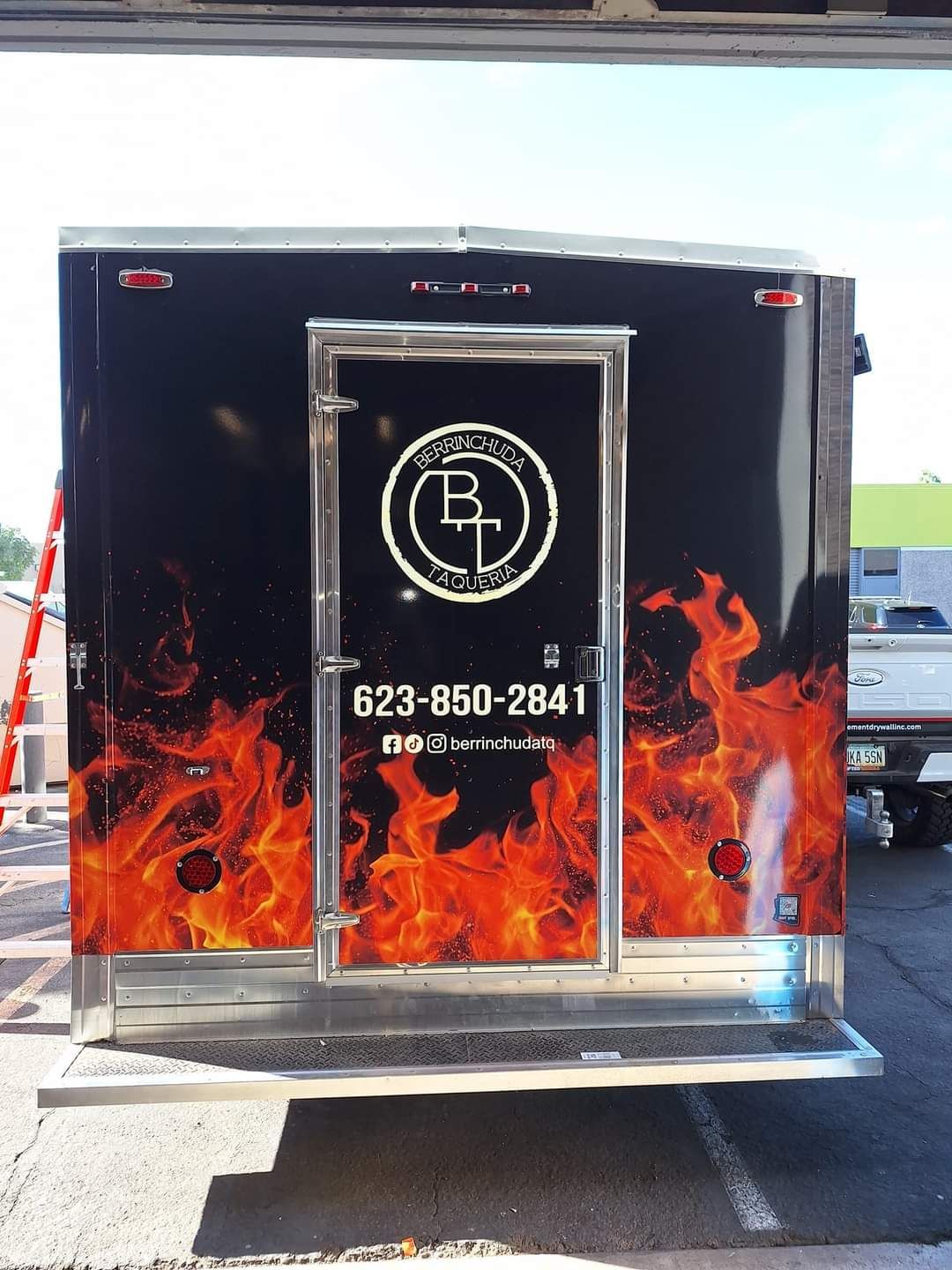 The back of a black trailer with flames on it