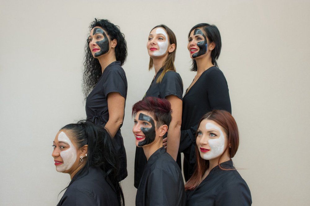 Team di estetiste con maschere viso nere e bianche