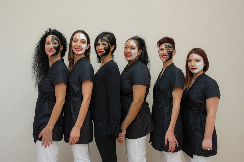 Team di estetisti con divisa bianca e nera e maschera sul viso