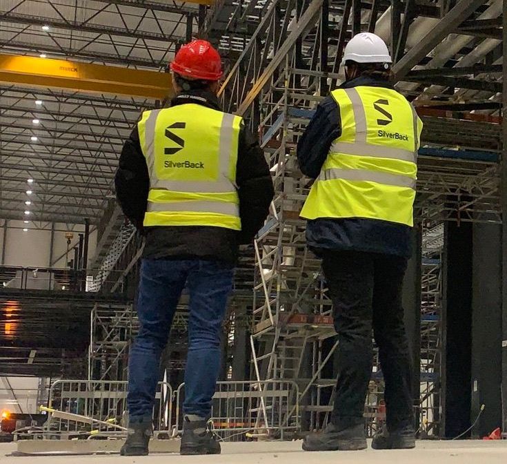Two men wearing yellow vests with the letter s on them