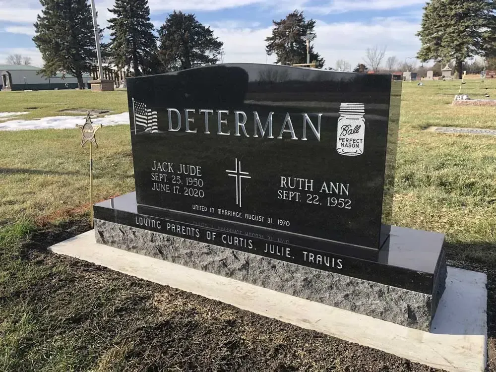 Black granite DETERMAN memorial headstone in a cemetery with trees and grass in the background