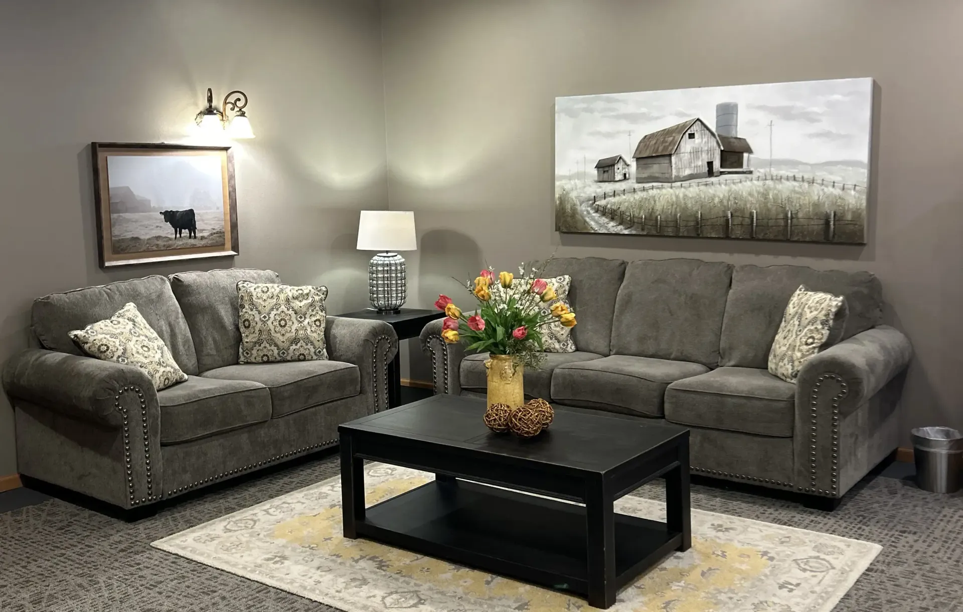 Cozy gray living room with two sofas, coffee table, lamp, rug, and wall art