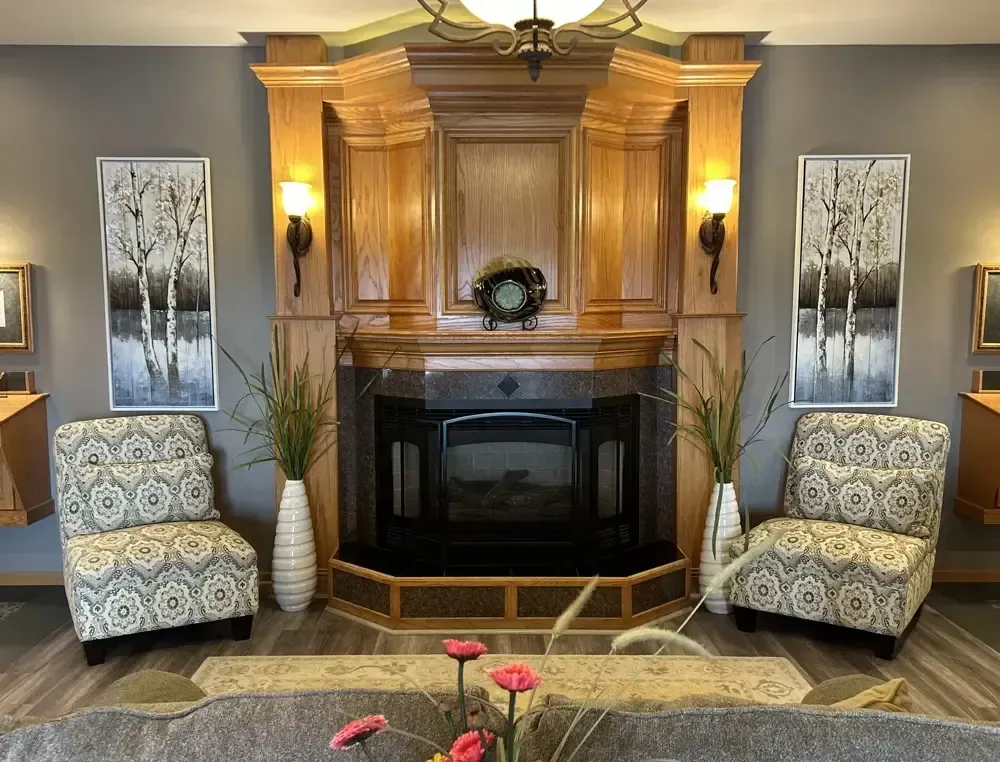 Elegant living room with a wood fireplace, patterned chairs, and wall art in warm lighting