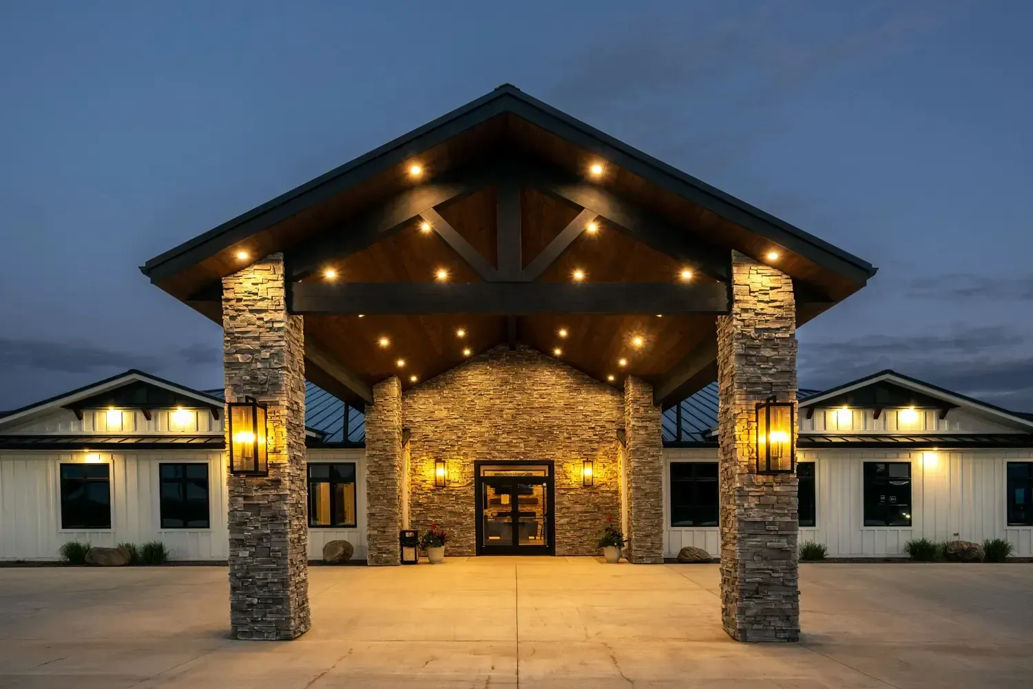 Lit stone building entrance with warm lights under a peaked roof at dusk