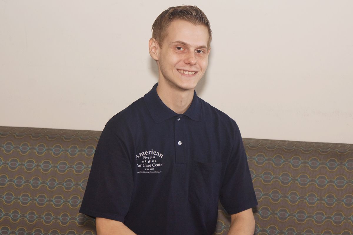 A young man in a blue shirt is sitting on a couch