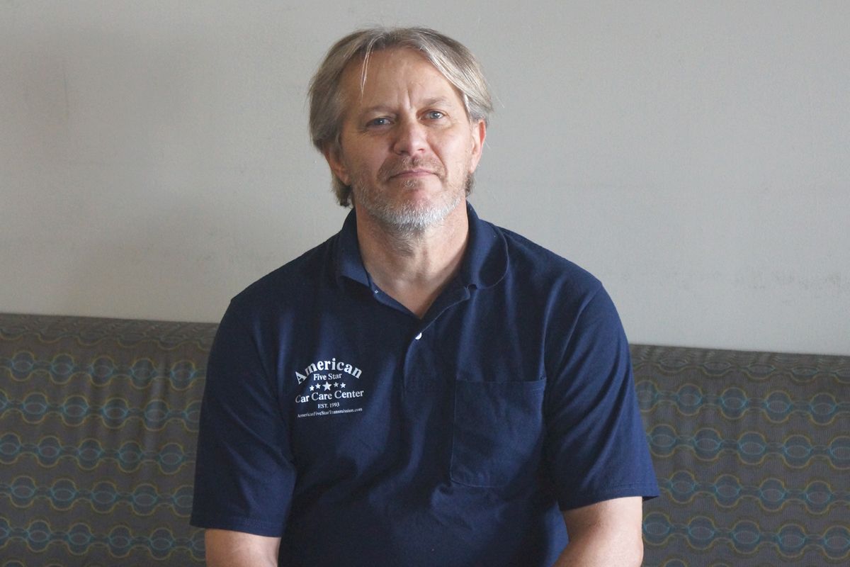 A man in a blue shirt is sitting on a couch