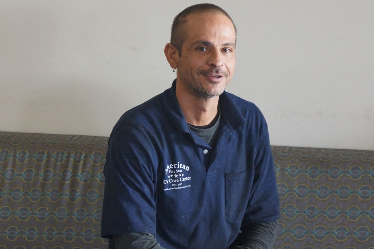 A man in a blue shirt is sitting on a couch