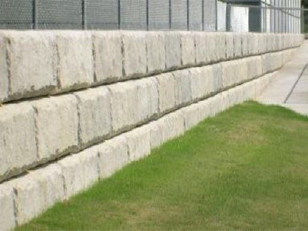 Long straight concrete block retaining wall bordering a grassy strip and sidewalk during a concrete block retaining wall service in Heber City, UT